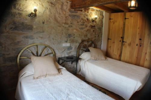 2 letti in una camera con parete in pietra di Vivienda Vacacional Los Picuos - Casas de los Picos a Robriguero