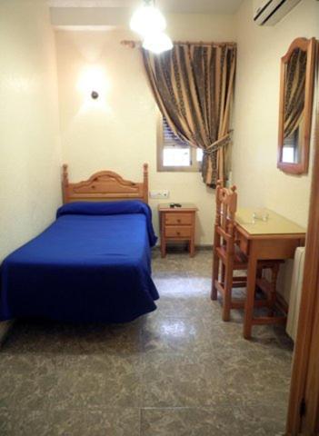a bedroom with a blue bed and a desk at Hostal Delfin Verde in Almería