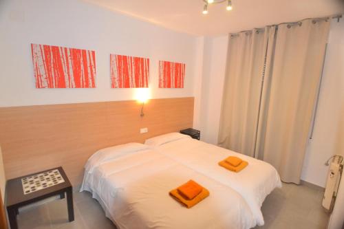 a bedroom with a bed with two orange towels on it at Apartamentos Marina Suites in Grao de Castellón