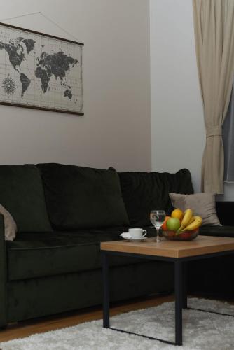 a green couch with a table with a bowl of fruit at Apartman Spas Titova Vila Zlatibor in Palisad