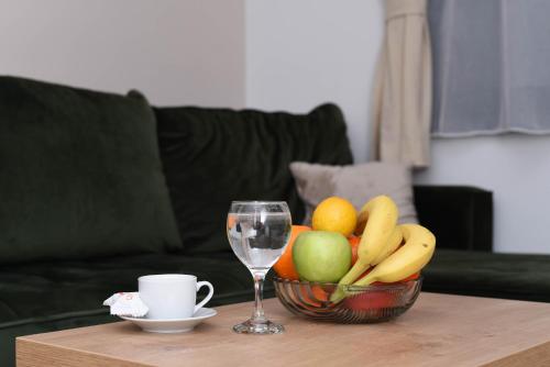 a bowl of fruit and a wine glass on a table at Apartman Spas Titova Vila Zlatibor in Palisad