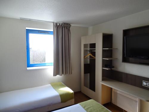 a hotel room with two beds and a flat screen tv at Euro Hôtel Airport Orly Rungis in Fresnes