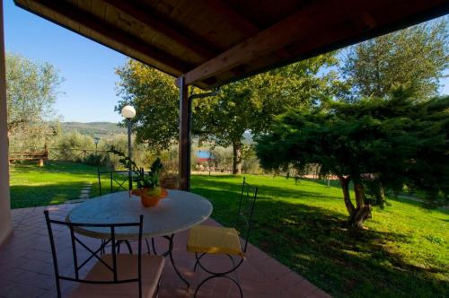 un patio con mesa, sillas y un árbol en Agriturismo Poggio Corbello, en La Pesta