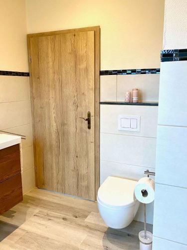 a bathroom with a toilet and a wooden door at Am Fuchsbau in Hallschlag