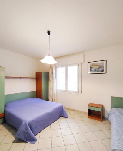 a bedroom with a blue bed and a window at Residence Stella Polare in Bibione