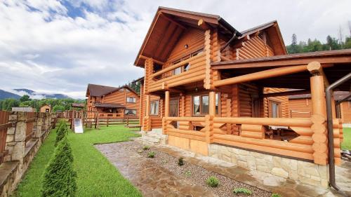 a log house with a fence and a yard at Cottage Simka in Mykulychyn