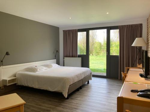 een slaapkamer met een bed en een groot raam bij Le Relais De La Haute Sambre in Lobbes