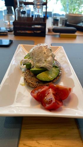 Un sándwich en un plato con pepinillos y tomate. en Hugo Hotel, en Satu Mare