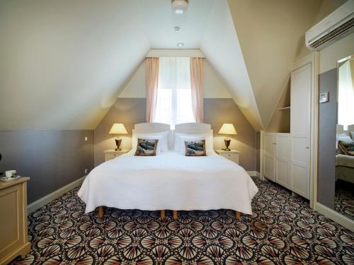 a bedroom with a white bed with two pillows at Villa Ammende Restaurant and Hotel in Pärnu
