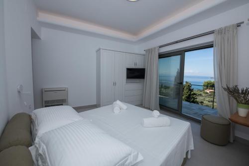 a white bedroom with a bed and a large window at Grand View Elios in Neo Klima