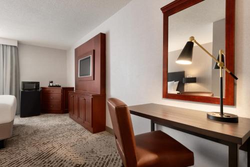 a hotel room with a desk and a mirror at Wingate by Wyndham South Bend - Notre Dame in South Bend