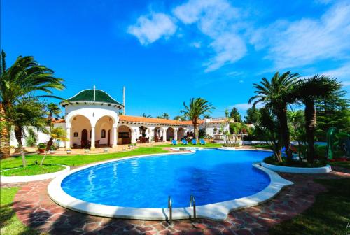 uma piscina em frente a uma casa com palmeiras em Villa Balneari Resort Casa de vacances familiar em Mont-roig del Camp