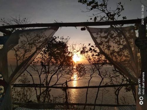 a view of the sunset from a porch with a fence at Bolo Beach Santorini nearby to Hundred Island in Alaminos