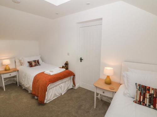 謝菲爾德的住宿－Holly Cottage，一间白色卧室,配有两张床和两盏灯。