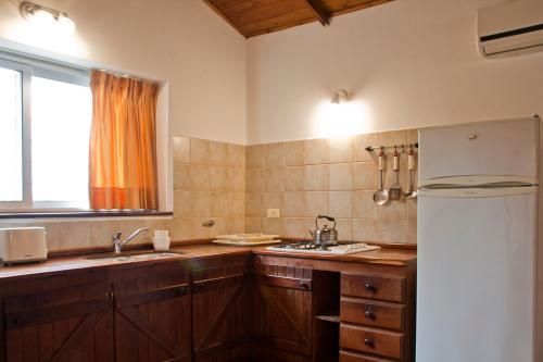 a kitchen with a white refrigerator and a window at Del Arroyo Cabañas in Villa General Belgrano