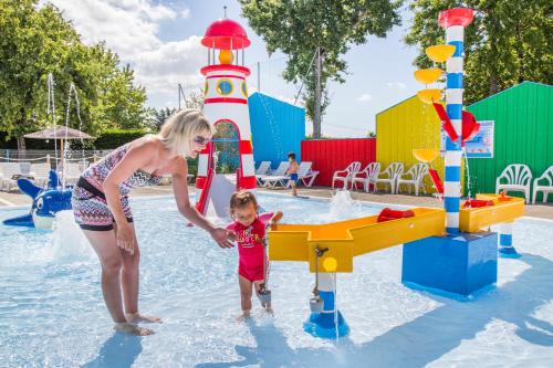 une femme et un enfant jouant dans un parc aquatique dans l'établissement Mobil Home XXL 4 chambres - Camping Le Domaine d'Oléron, à Foulerot