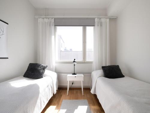 Dos camas en una habitación con ventana. en Kansankatu Apartments, en Rovaniemi