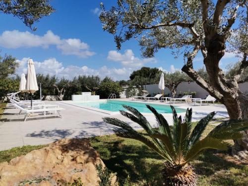 a pool with chairs and umbrellas in a resort at Signorino Eco Resort & Spa in Marsala