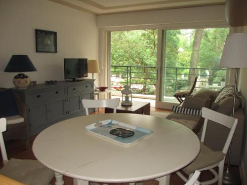 sala de estar con mesa, sillas y ventana grande en Appartement Pour 4 Personnes- Residence Sporting House, en Hossegor