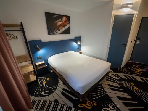 a small room with a bed and a mirror at Welcomotel Beauvais Aéroport in Beauvais