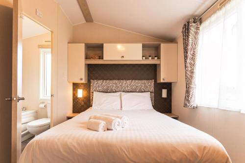 a bedroom with a large bed with towels on it at Meadows Lodge with Hot Tub in Malton