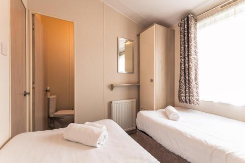 a small room with two beds and a window at Meadows Lodge with Hot Tub in Malton