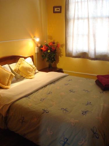 a bedroom with a bed with a vase of flowers on it at Blue House Youth Hostel in Quito