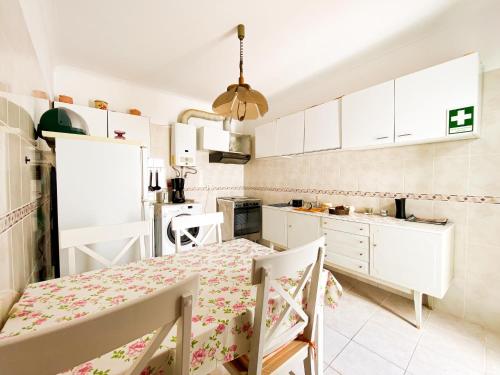 a kitchen with white cabinets and a dining table at Simple Beach Lovers' Retreat in Espiche #1888 in Espiche