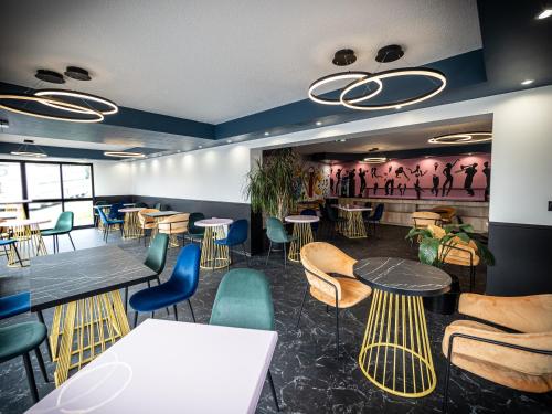 a restaurant with tables and chairs and a painting on the wall at Welcomotel Beauvais Aéroport in Beauvais