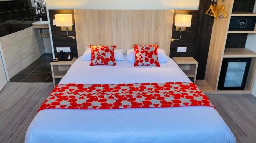 a bedroom with a large bed with red pillows at Hotel Martinez Grenay in Grenay