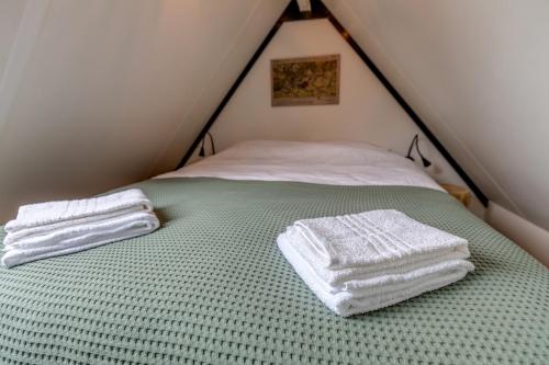 a bed with two towels sitting on top of it at B&B Larenstein logeren in een tiny house in Velp