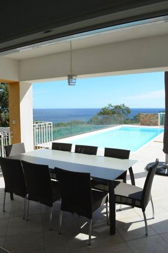 a table and chairs on a patio with a swimming pool at Residence Mare e Monte in Favone