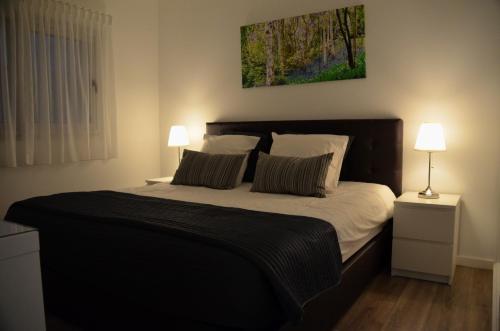 a bedroom with a large bed with two lamps at Cazenn Nazaré - Apartment Z in Nazaré