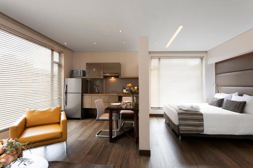 a bedroom with a bed and a table and a kitchen at bs Rosales Hotel in Bogotá