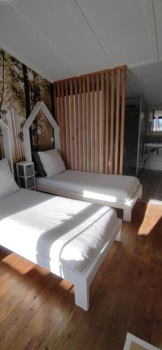 two beds in a room with wooden floors at Les Chalets Du Goulet in Le Bleymard