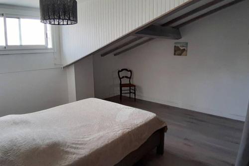 um quarto branco com uma cama e uma cadeira em Villa Argentine T2 classé 2* thème Beach em Dax