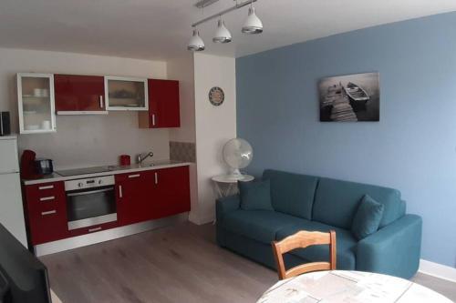 uma sala de estar com um sofá azul e uma cozinha em Villa Argentine T2 classé 2* thème Beach em Dax