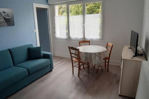 uma sala de estar com um sofá azul e uma mesa e cadeiras em Villa Argentine T2 classé 2* thème Beach em Dax