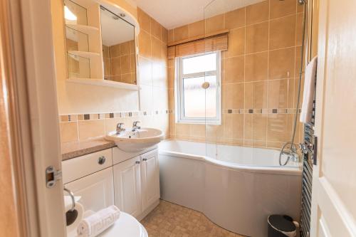 a bathroom with a sink and a bath tub at Saffron Lodge With Hot Tub in Malton