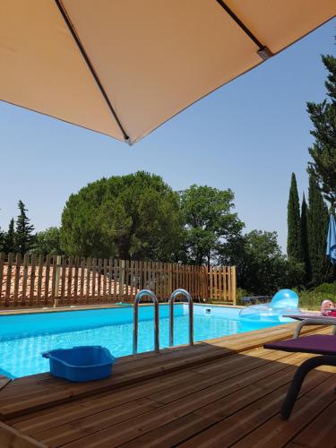 - une piscine avec un parasol sur une terrasse en bois dans l'établissement Mas Orféo, à Montauroux