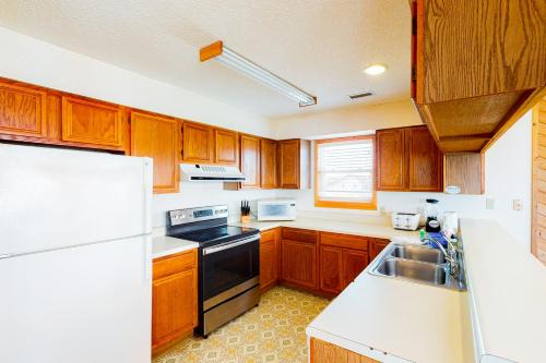 a kitchen with wooden cabinets and a white refrigerator at Harper House #4BB in Buxton