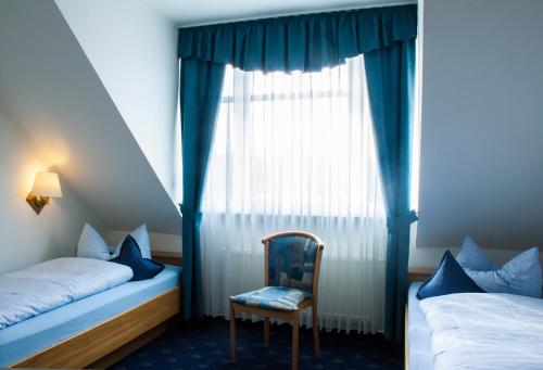a bedroom with two beds and a chair and a window at Hotel Restaurant Bergeshöhe in Mettingen