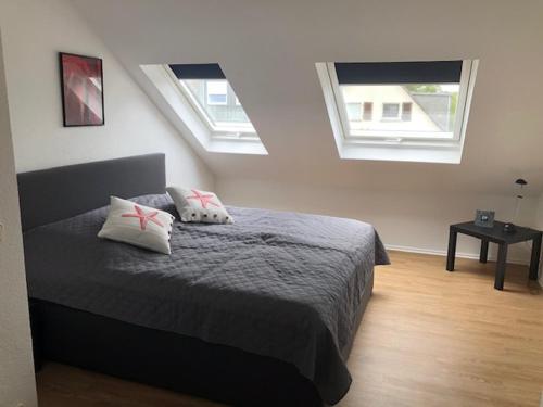 a bedroom with a bed with two pillows and two windows at Ferienwohnung Bergisch Gladbach in Bergisch Gladbach