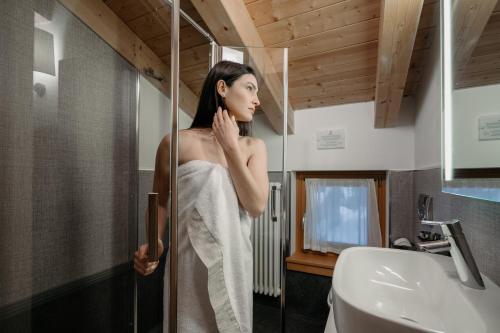 uma mulher na casa de banho a olhar-se ao espelho em Hotel Chalet Del Brenta em Madonna di Campiglio