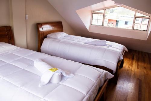 two beds in a small room with a window at Hotel Imperial Zumbahua & Quilotoa Lodge in Zumbahua