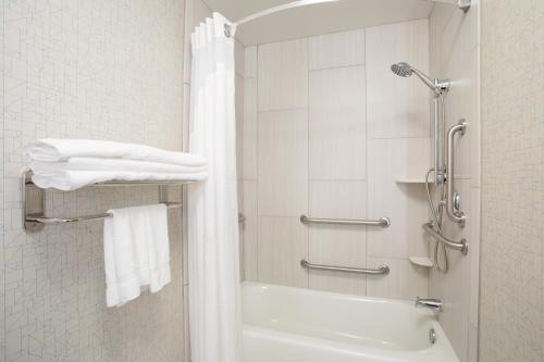 a bathroom with a white tub and a shower with towels at Holiday Inn Express Hotel & Suites Longmont by IHG in Longmont