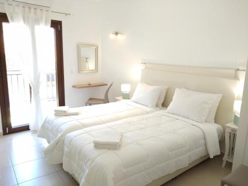 ein weißes Schlafzimmer mit einem großen weißen Bett mit weißen Kissen in der Unterkunft Stylish home - comfortable holidays near the beach. in Panormos