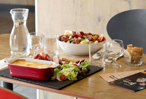 a table with a salad and a bowl of food at ibis budget Clermont Ferrand Nord Riom in Riom