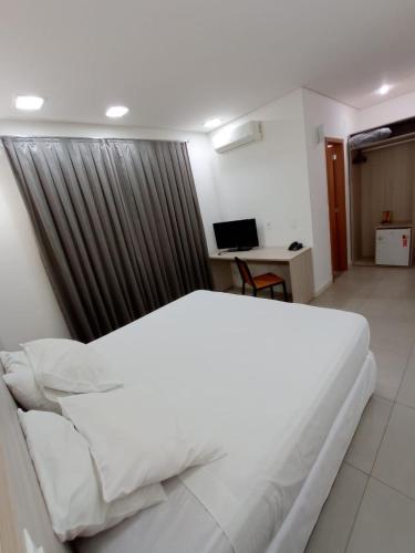 a large white bed in a room with a desk at Hotel Manacá in Sacramento