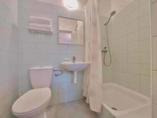a white bathroom with a toilet and a sink at Pod Różą Economy in Łeba